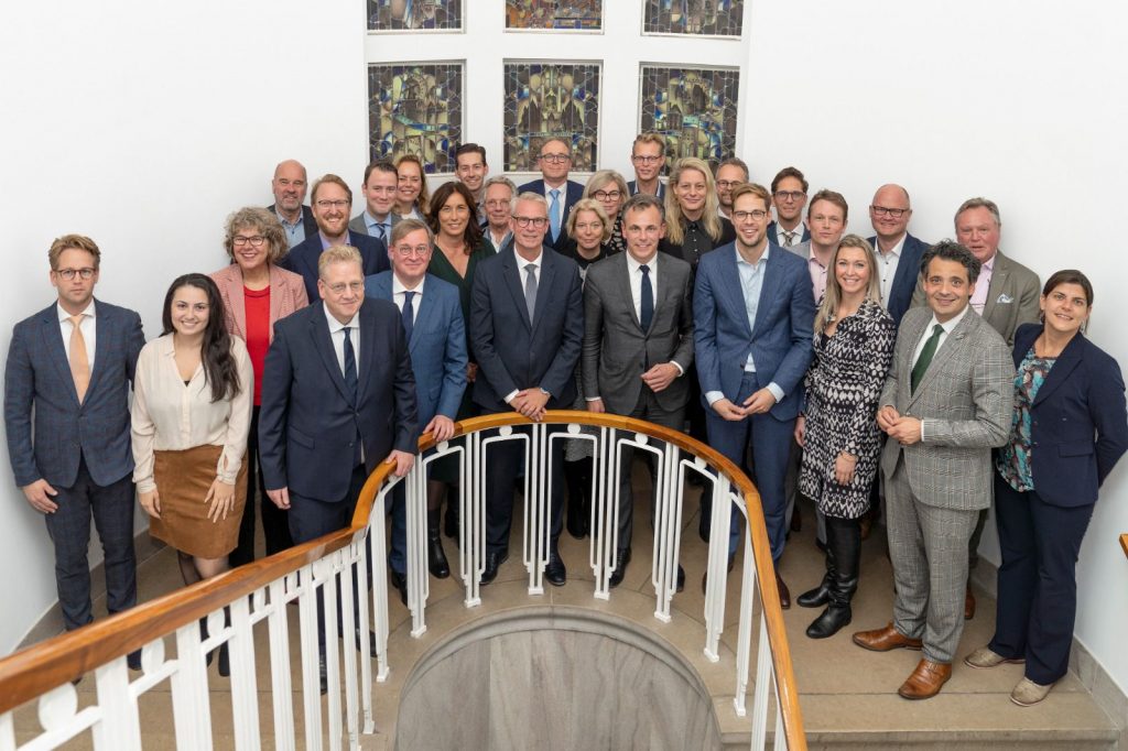 Minister Harbers omringd door de leden van de Bestuurlijke Regie Schiphol, waaronder wethouders van de gemeenten uit de regio Alkmaar-BUCH-Haarlem-IJmond