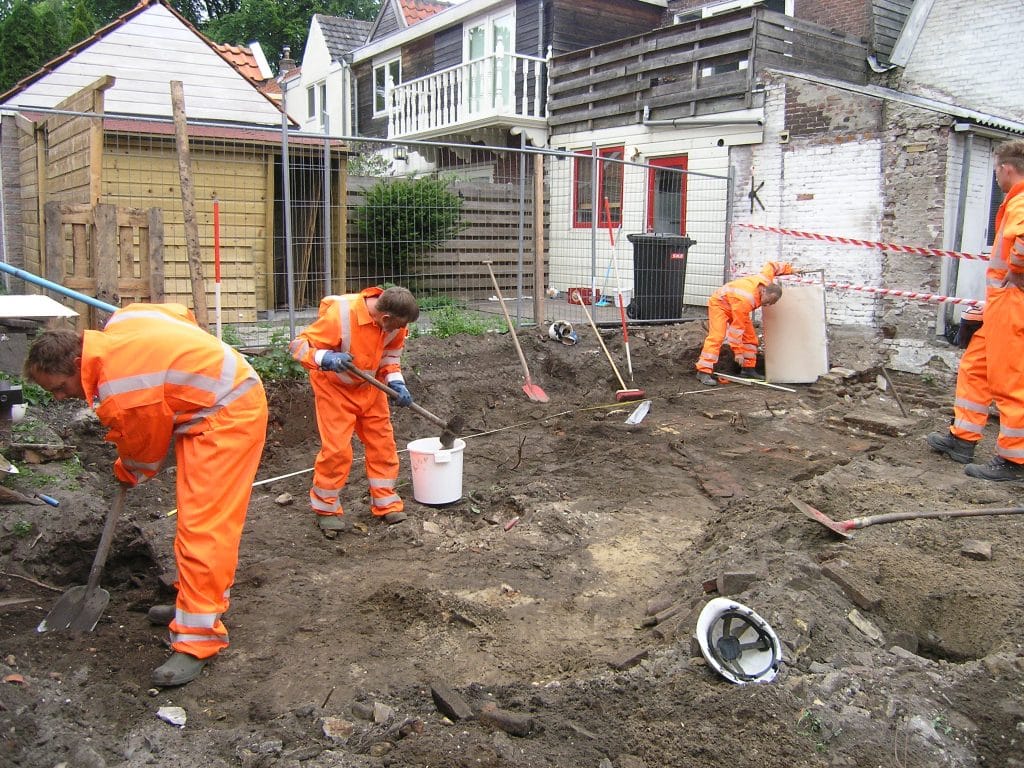Groep mensen in oranje pakken doet opgravingen 