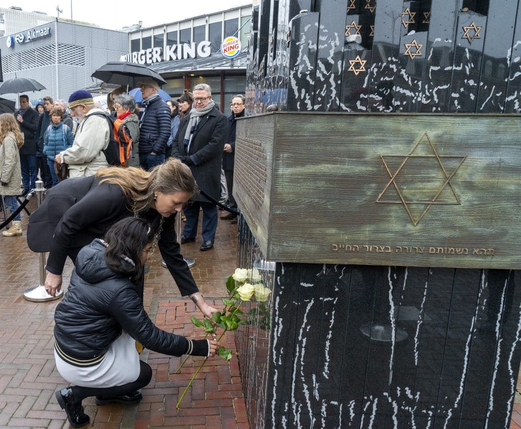 Burgemeester en kinderburgemeester leggen bloemen bij monument