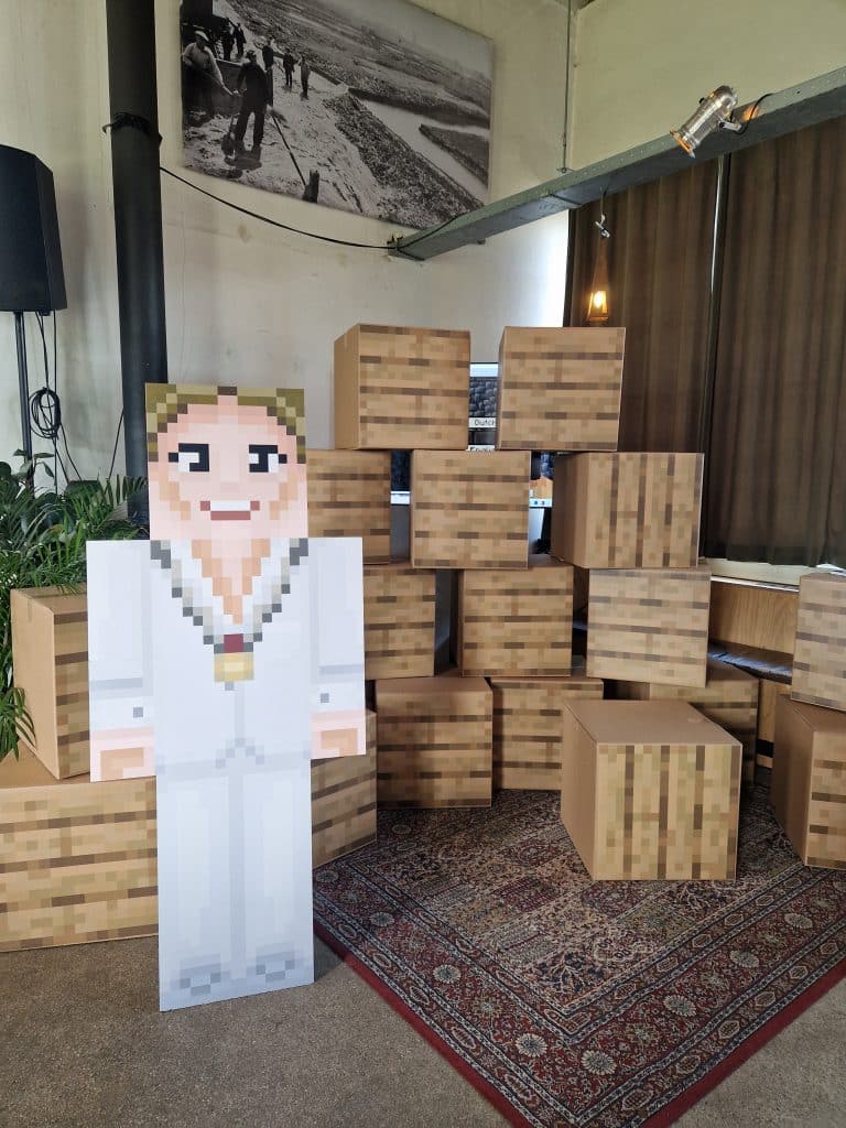 Burgemeester Anja Schouten als Minecraft figuur voor de blokkenmuur die wethouder Schouten met de kinderen doorbrak om het project te openen.