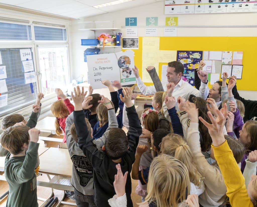 Wethouder Christiaan Peetoom reikt een certificaat uit aan een groep leerlingen van De Regenboog