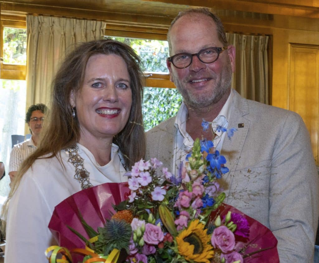 Peter Visser (rechts) met bloemen en burgemeester Anja Schouten na de uitreiking van het gouden Ere-insigne van de stad Alkmaar. Foto JJFoto