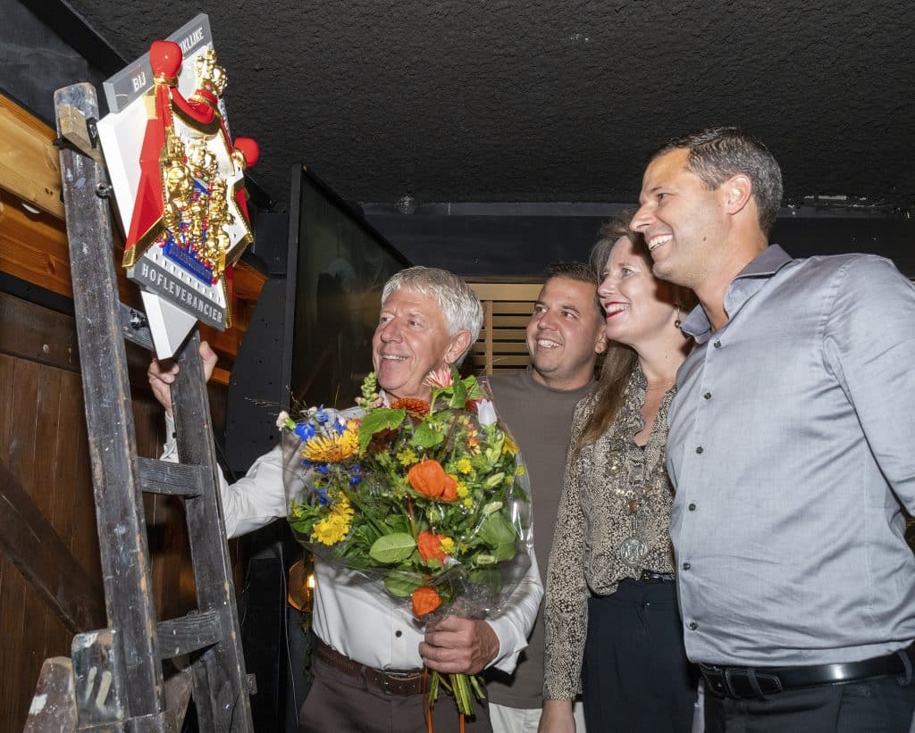 Links op de foto het Predikaat Hofleverancier op een ladder met vader Han Schipper. Burgemeester Anja Schouten en Vincent en Pascal Schipper kijken toe. Foto gemaakt door JJFoto