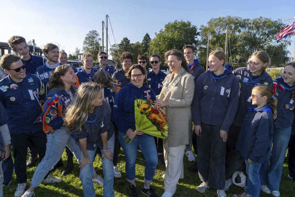 Gedecoreerde Mirjam van der Laan met bloemen. Naast haar burgemeester Anja Schouten. ZIj zijn omring door leden van Scoutinggroep Marco Polo Foto: JJFoto