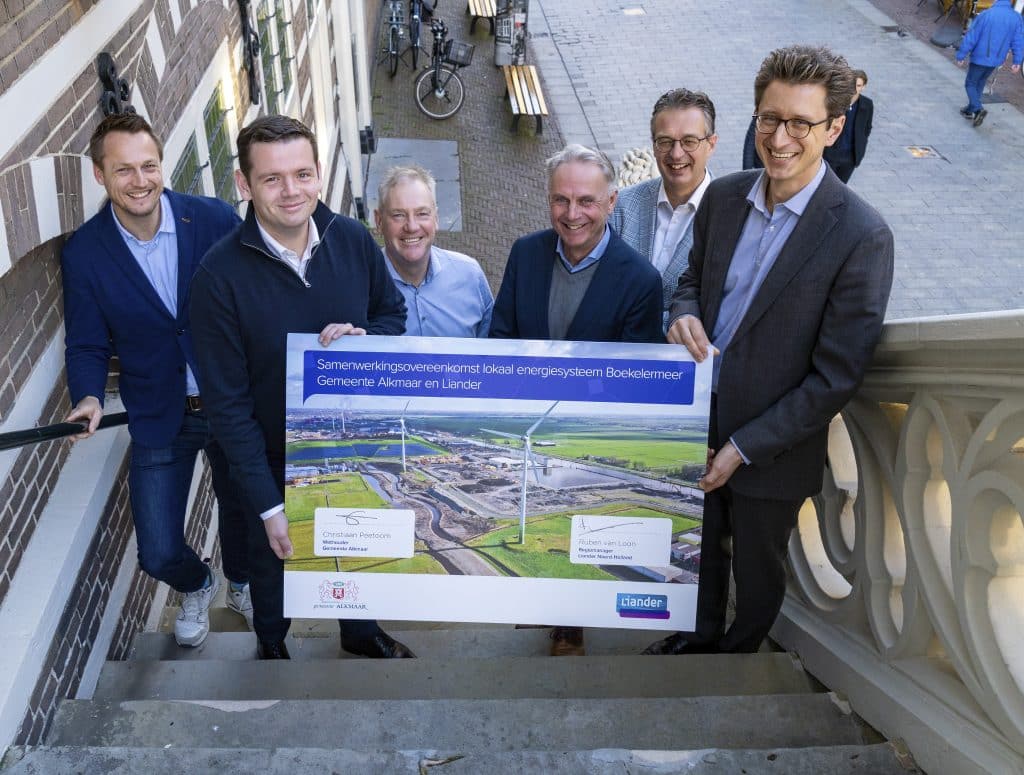 Op de trap van het stadhuis van Alkmaar staat een groep mensen. Wethouder Christiaan Peetoom en Ruben van Loon van Liander tonen hetondertekende contract. Foto is gemaakt door JJFoto.