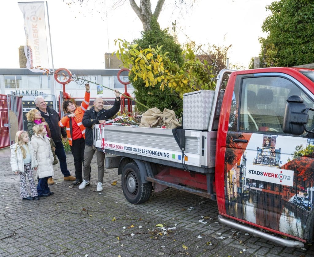 Een groepje van 6 mensen legt een boom op een vrachtwagen van Stadswerk072.