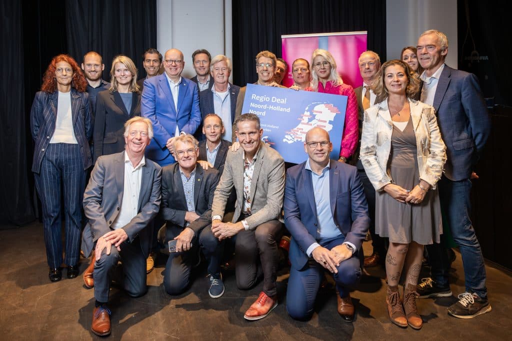 Foto van groep mensen die een bord vasthouden met tekst erop, namelijk 'Regio Deal Noord Holland Noord".