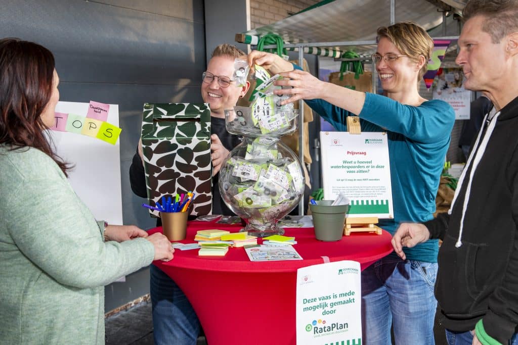 Vier mensen staan bij een statafel. 