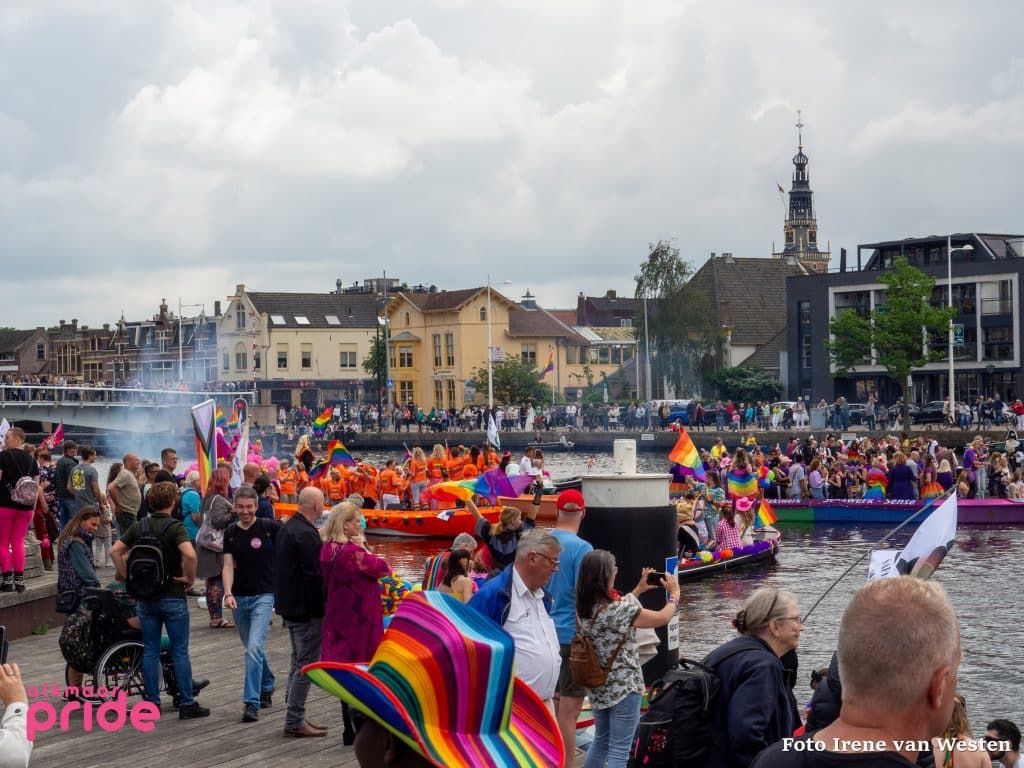 Toeschouwers kijken naar boten tijdens de grachtenparade van de Alkmaar Pride 2024