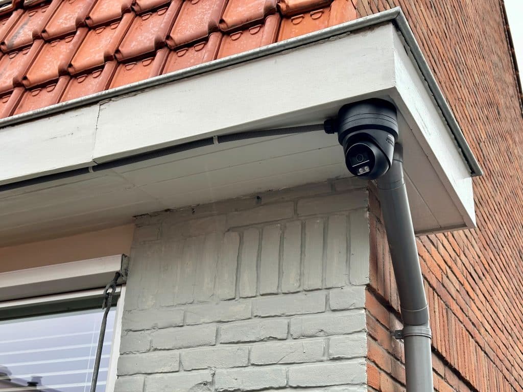 Een zijaanzicht van een huis met een beveiligingscamera bevestigd onder de dakgoot.