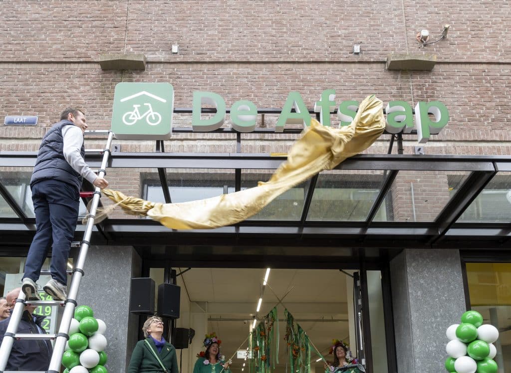 Wethouder Christiaan Peetoom onthult de naam "De Afstap" van de nieuwe fietsenstalling aan de Laat.