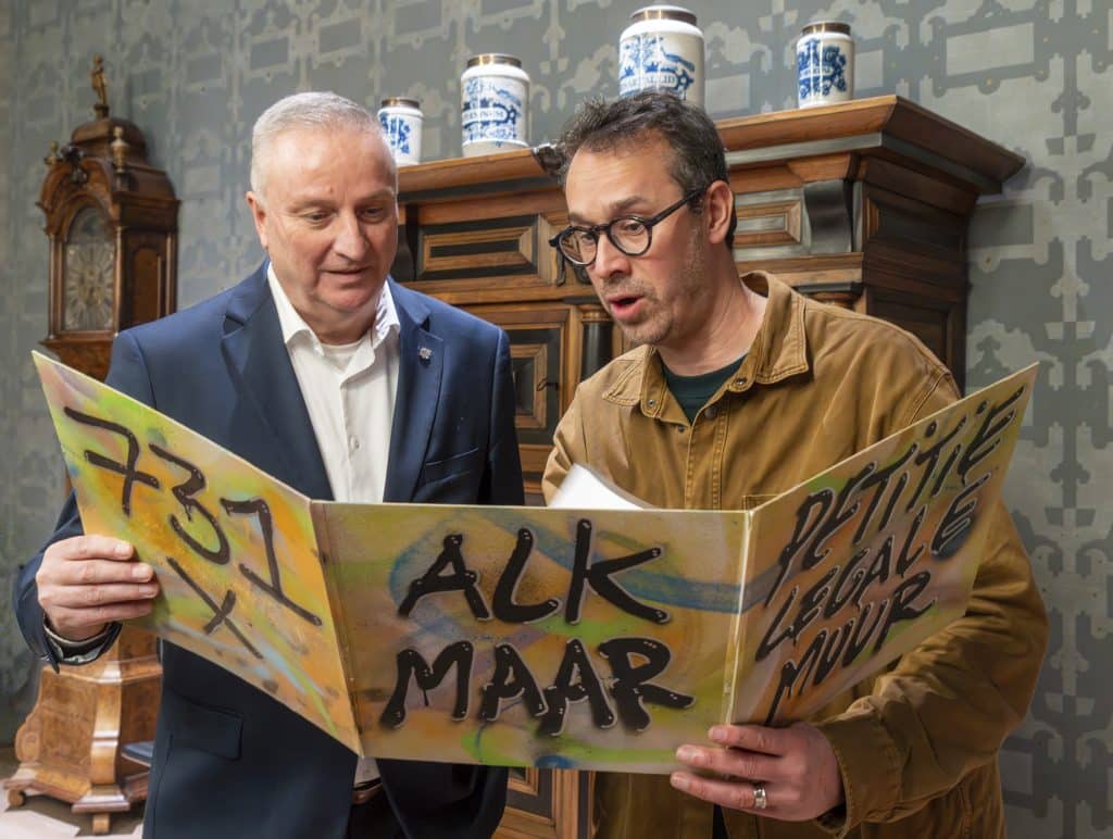 Twee mannen lezen uit een grote petitie. Het is een petitie voor een legale graffitimuur in Alkmaar. De kaft is versierd in graffitistijl. (foto:JJFoto)