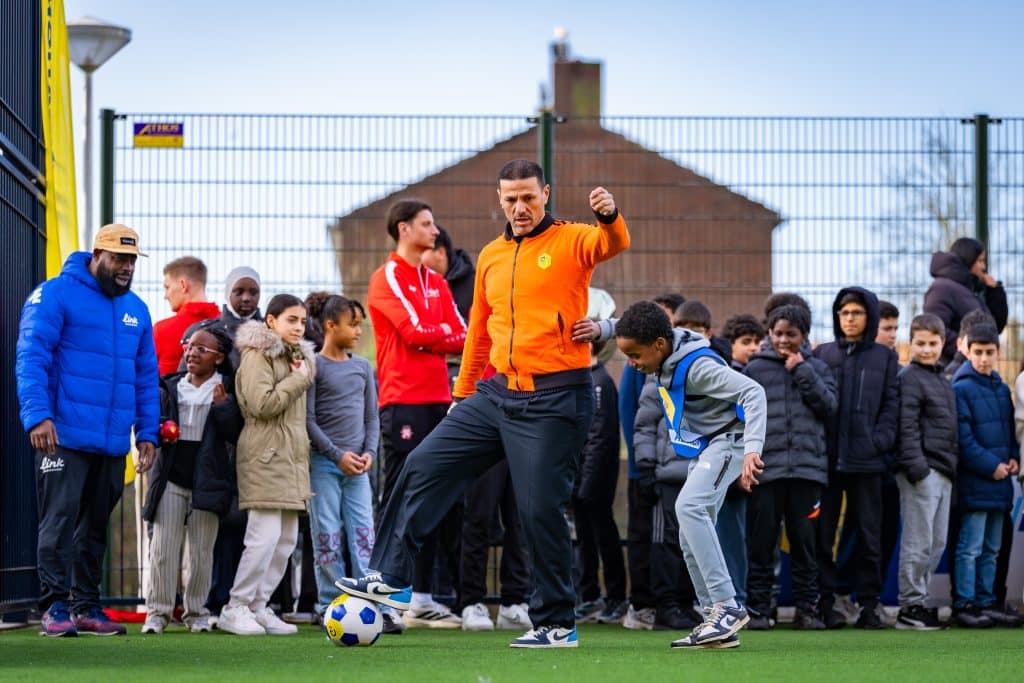 Een voetballer en een kind spelen samen voetbal op het Cruyff Court in Overdie tijdens de opening.