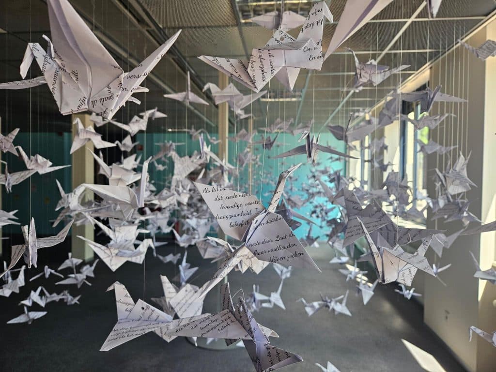 Op de foto staan gevouwen papieren kraanvogels met de tekst van artikel 1 van de Grondwet.