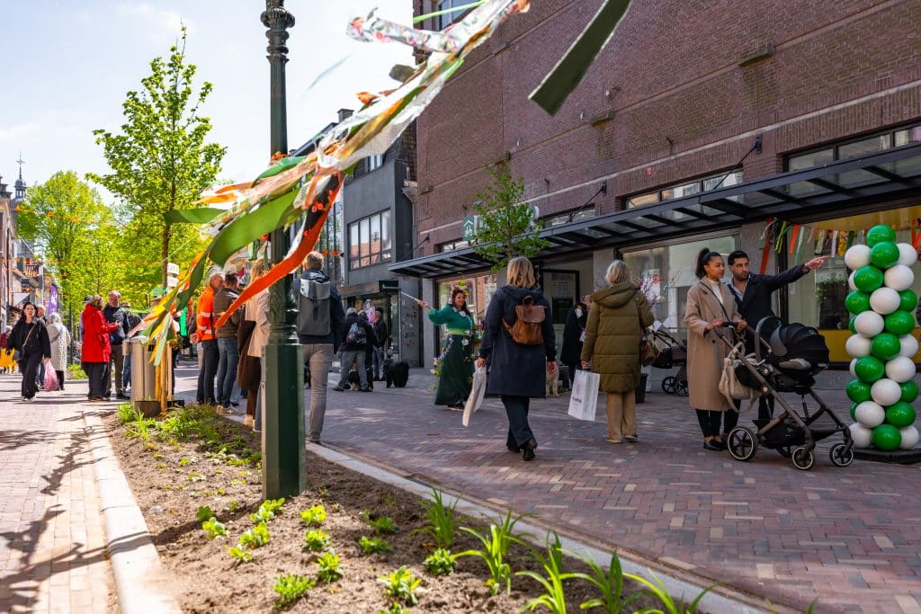Bezoekers lopen over de vernieuwde Laat-midden in Alkmaar langs winkels, met nieuw groen en plantenbakken langs de straat.